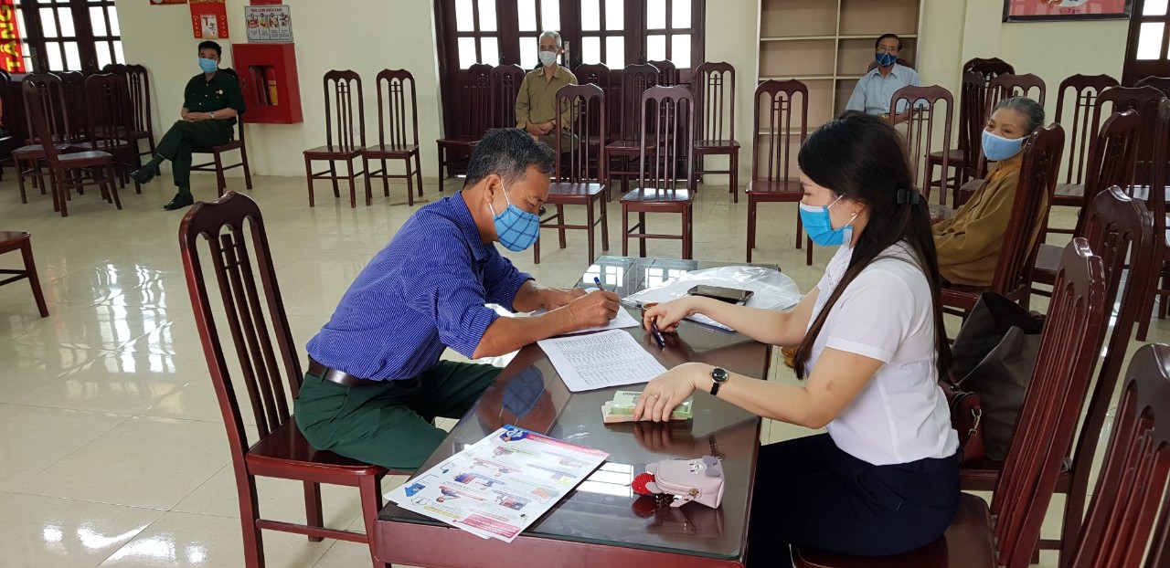 Cán bộ chi trả tiền trợ cấp cho người dân