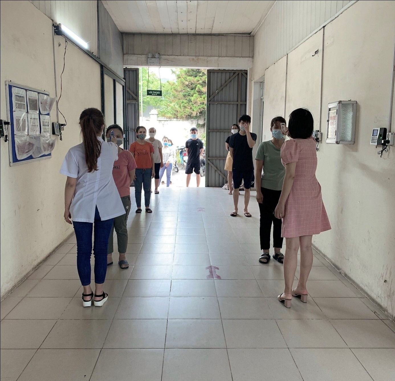 Công nhân công ty Trách nhiệm hữu hạn D- CODE được đo thân nhiệt trước khi vào làm việc.
